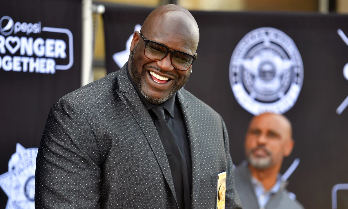 Shaquille O’Neal smiling and laughing on the red carpet at an NBA event.