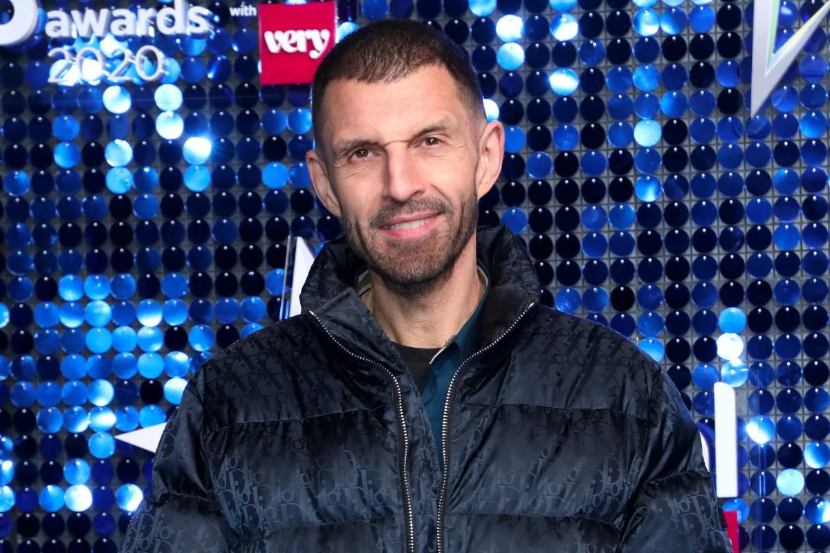 Tim Westwood poses on the red carpet, dressed in a puffer jacket and smiling for photographers.