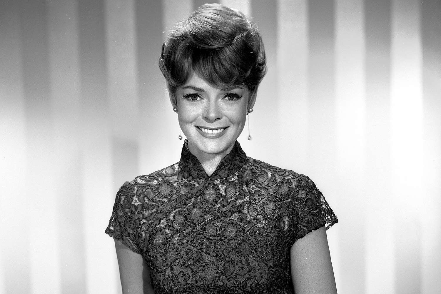 Black and white photograph of a young June Lockhart smiling at the camera, exuding charm and warmth.