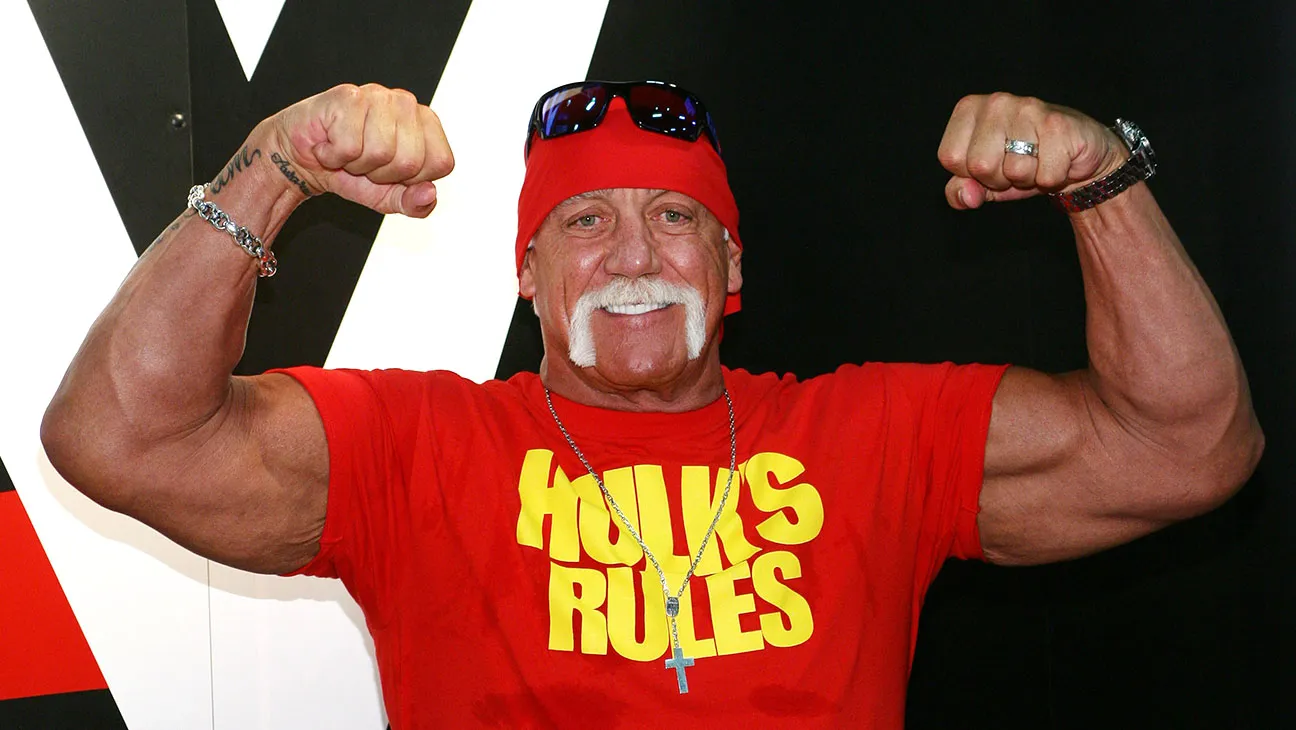 Hulk Hogan flexing his muscles, showcasing his iconic physique and intense expression during a wrestling event.