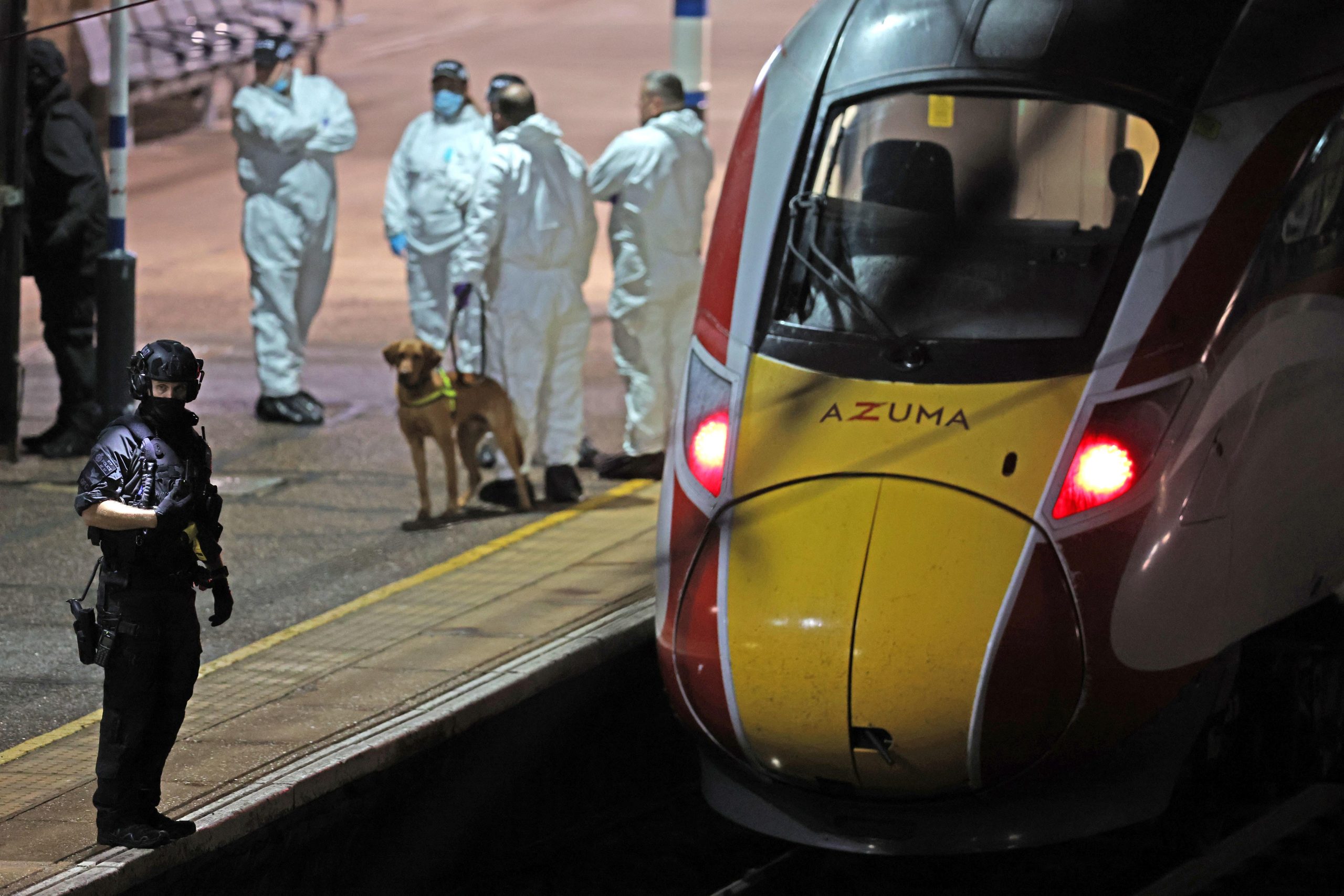 Forensic officers and police standing outside the Cambridgeshire train following the mass stabbing incident.
