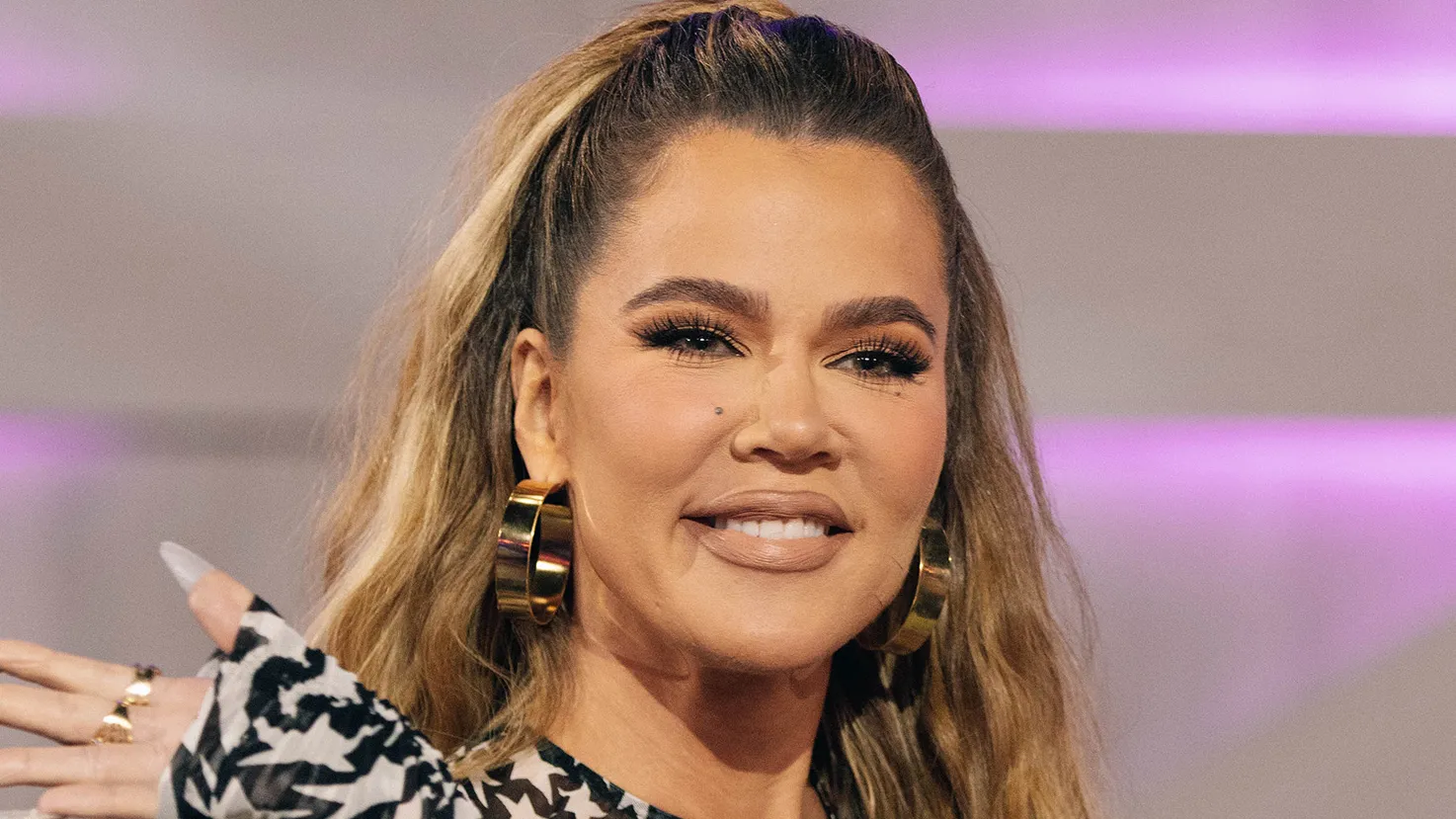 Khloé Kardashian smiling warmly during a photoshoot, exuding confidence and glamour.
