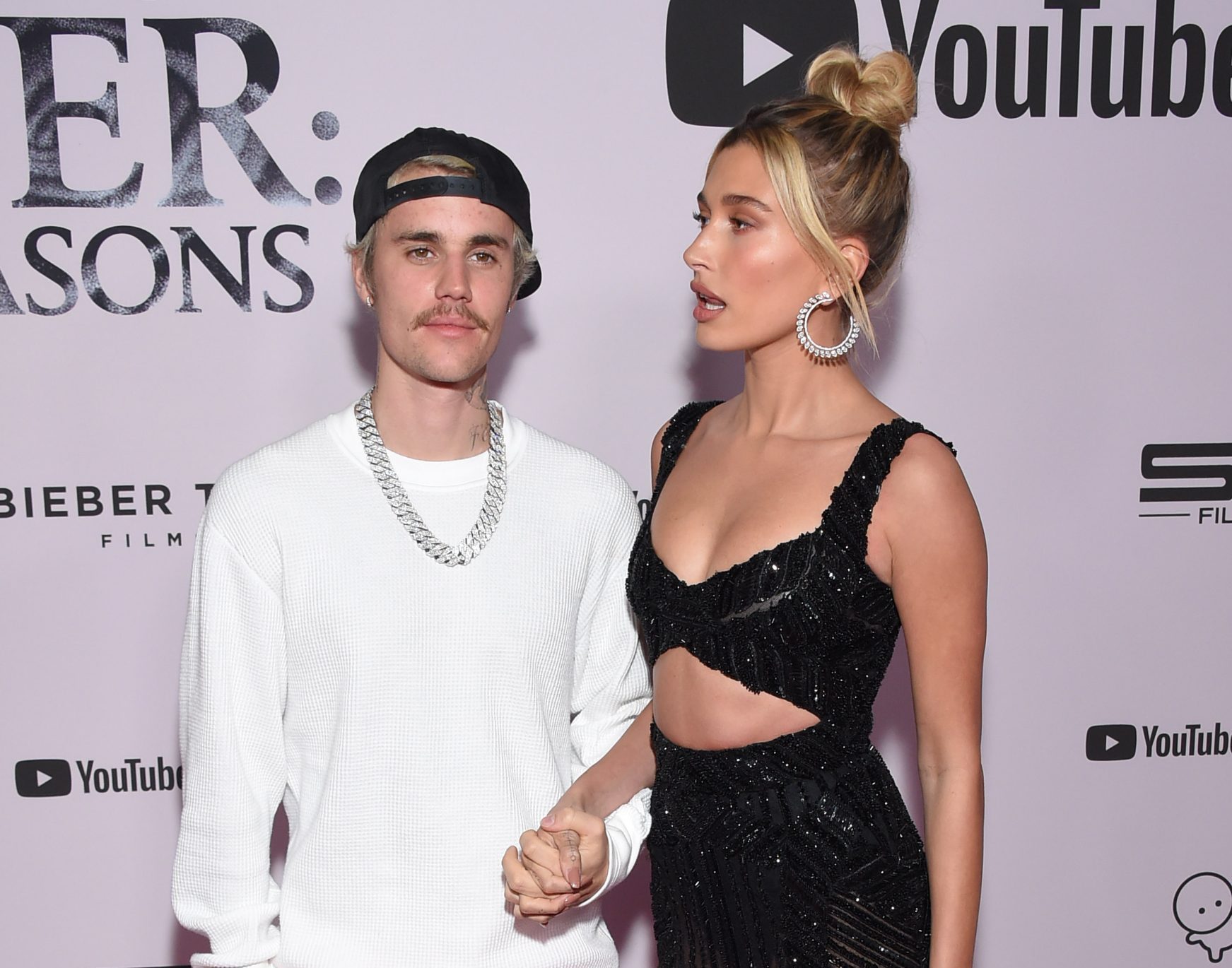 Justin and Hailey Bieber posing together on the red carpet, dressed in stylish evening attire.