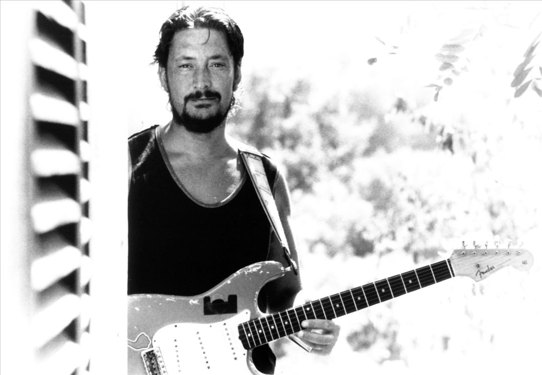 Black-and-white portrait of Chris Rhea holding his guitar, looking thoughtful and reflective.
