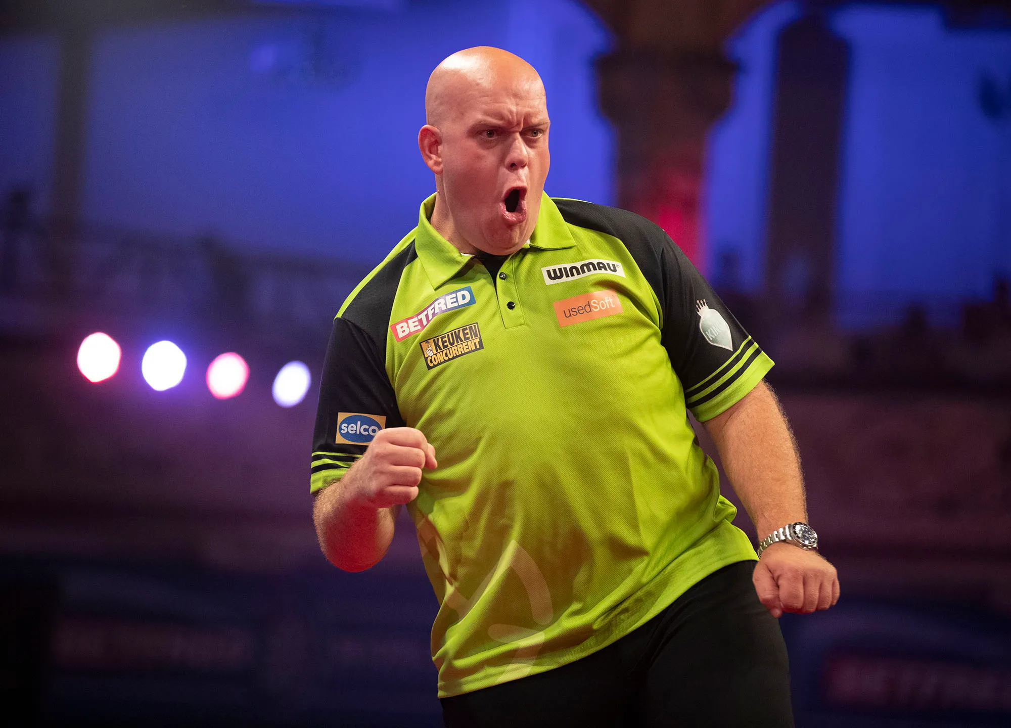 Michael van Gerwen performing his classic “Boom!” celebration, fist clenched and arms raised after hitting a big score.