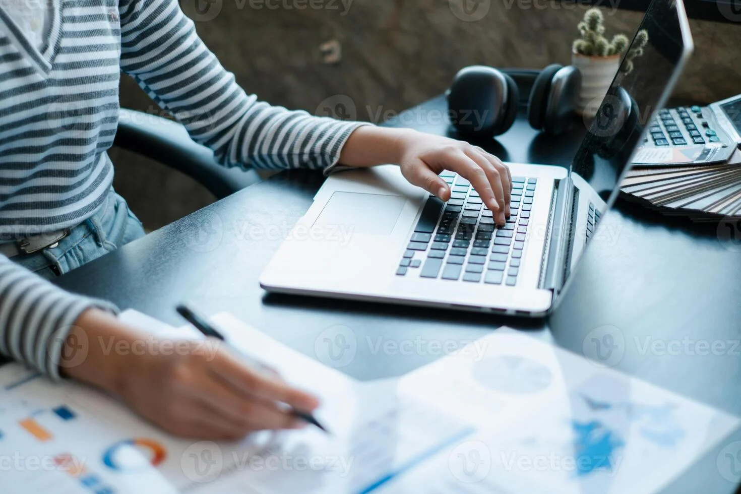 a person working on a laptop while reviewing financial documents showcasing a professional office environment photo