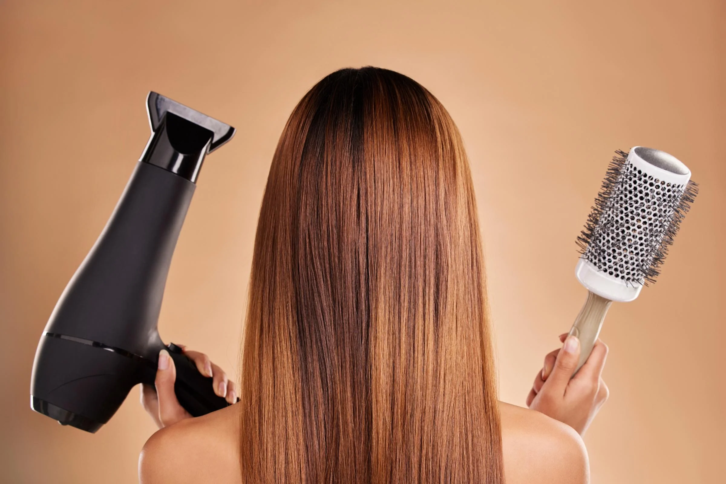 Woman holding a hairbrush and hair dryer looking confused about how to src her hair.