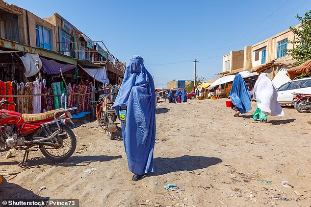 The Taliban's morality police have rounded up at least nine females over the past two days in Afghanistan. Pictured: An Afghan woman wearing a burqa walks along a market in Andkhoy, Faryab Province, Northern Afghanistan