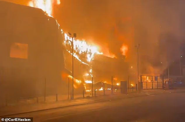 This is the moment a burning building came crashing down after a blaze ripped through a fashion outlet loved by sports stars and soap actors